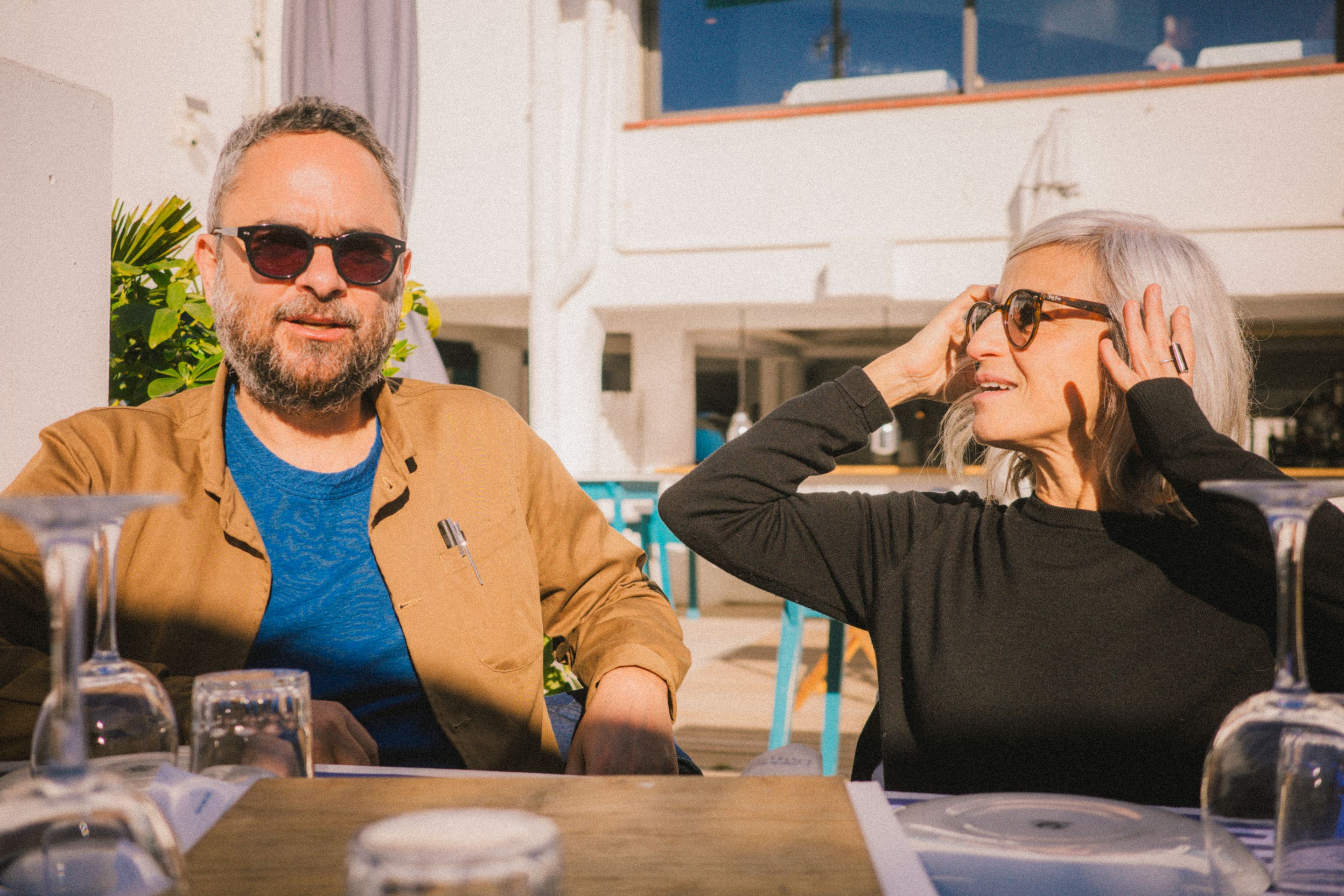 Retrato de Orlando y Laura sentados a la mesa del restaurante. Orlando mira a la cámara y Laura mira a Orlando.